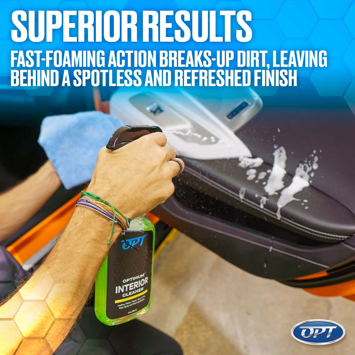 A person's hand with colorful braided bracelets holding a green Optimum Interior Cleaner spray bottle applying fast-foaming white cleaning product to a black car door panel with white stitching, a blue microfiber towel nearby, illustrating superior results