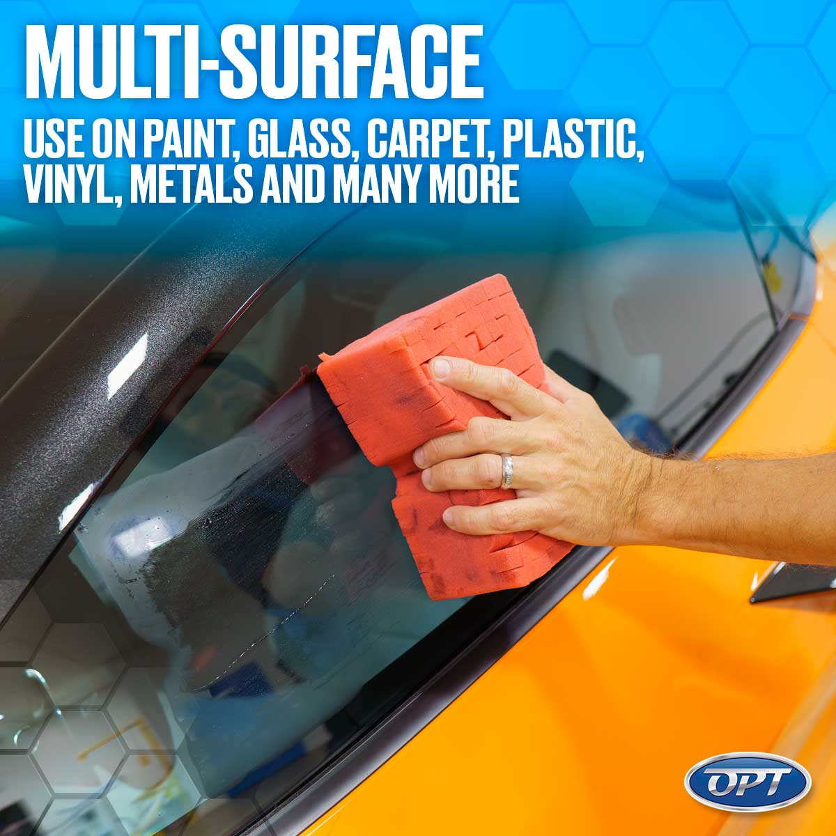 Photography of a hand with a silver ring cleaning the windshield of a vibrant orange car using a red textured sponge, with white text overlay MULTI-SURFACE USE ON PAINT GLASS CARPET PLASTIC VINYL METALS AND MANY MORE and an OPT logo